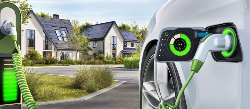 Electric car charging stations. Modern houses with photovoltaic